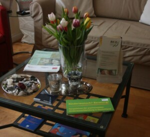 Blumen und Flyer auf Glasstisch im Praxisraum der Kinderwunschberatung Bremen